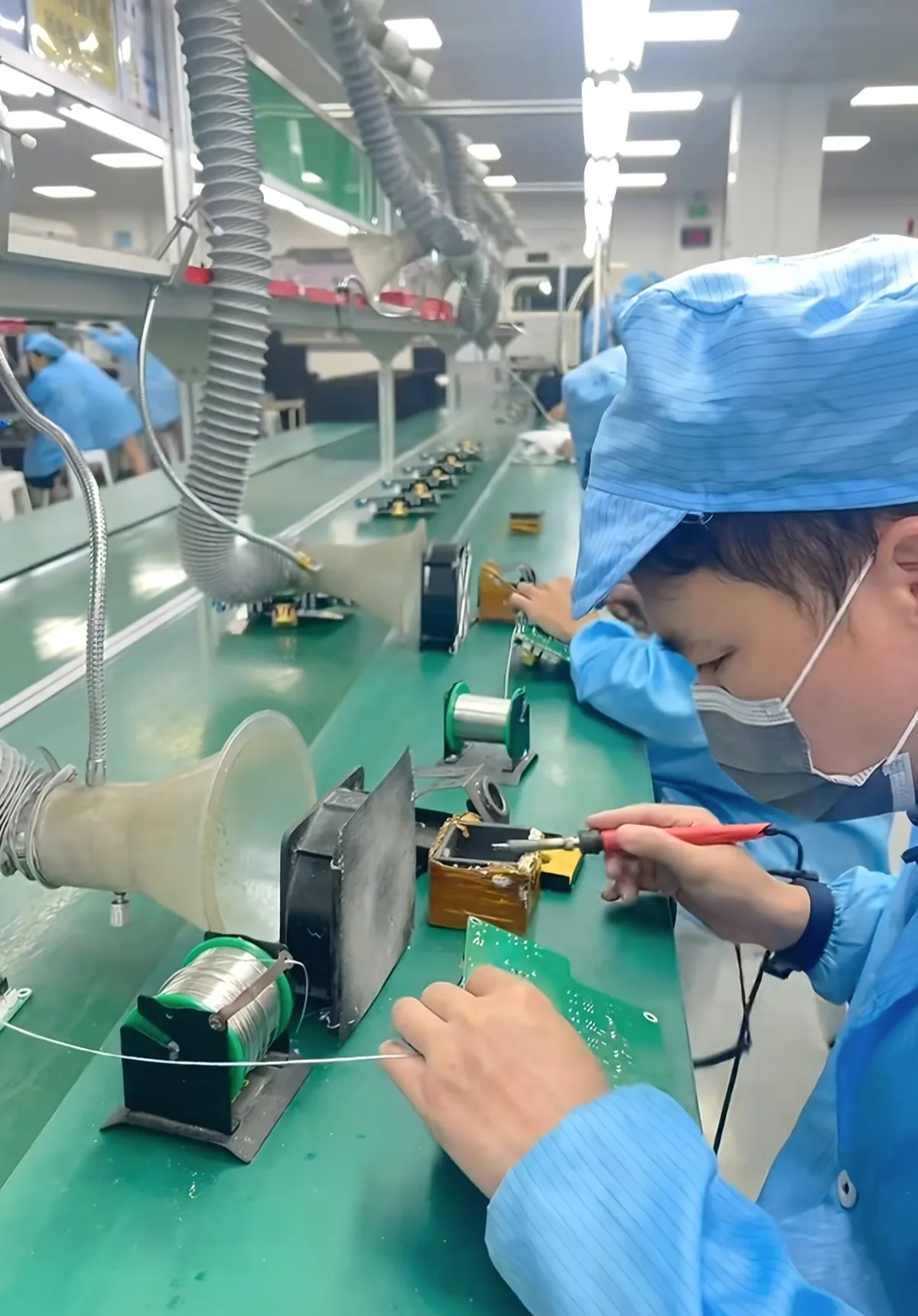 Operator soldering through-hole components on a PCBA production line
