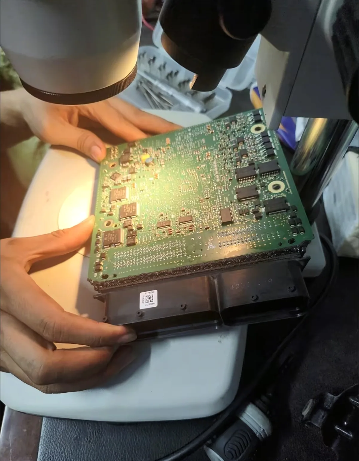 Technician examining an assembled PCBA under a microscope
