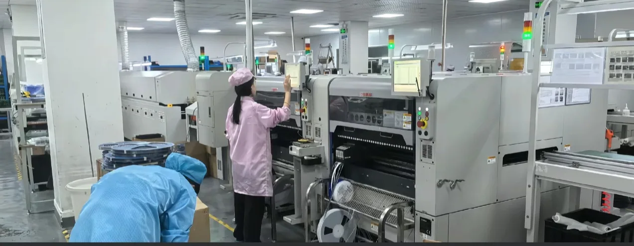 Operators working beside an SMT placement line for PCBA assembly