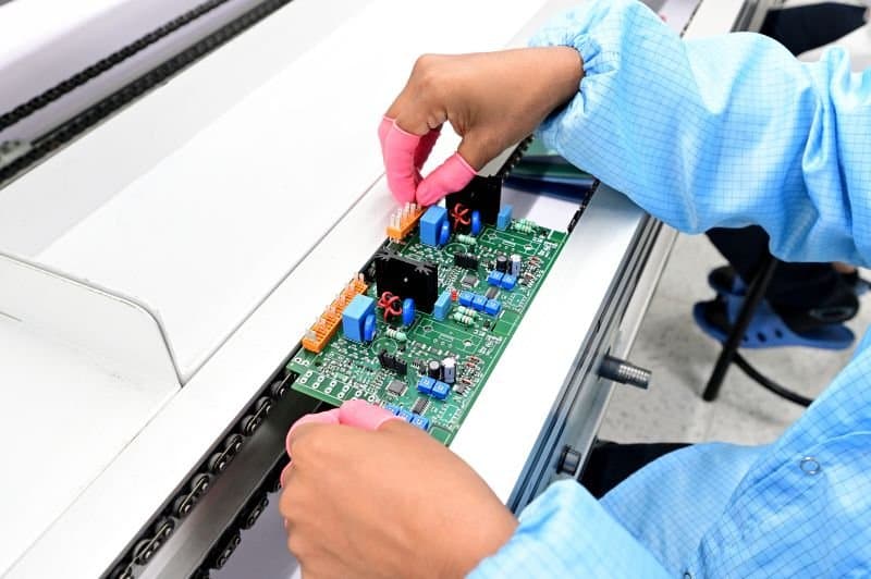 Hands placing through-hole components on a circuit board